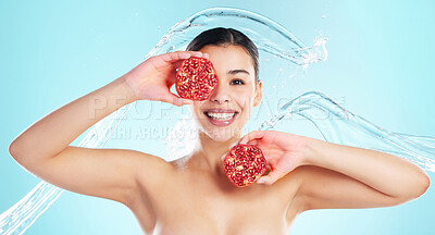 Buy stock photo Studio portrait of an attractive young woman posing with a pomegranate in her hand against a blue background
