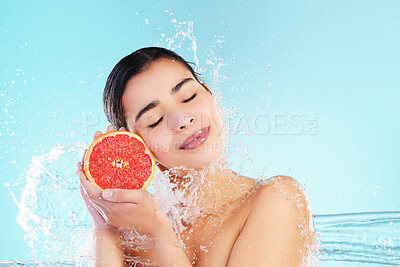 Buy stock photo Studio portrait of an attractive young woman posing with a grapefruit in her hand against a blue background