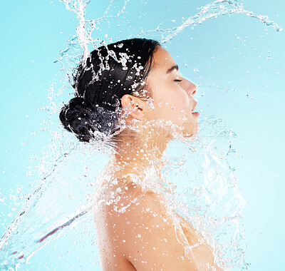 Buy stock photo Shot of a beautiful young woman being splashed with water against a blue background