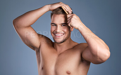 Buy stock photo Shot of a handsome young man combing his hair