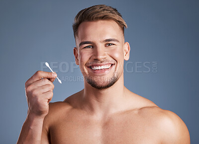 Buy stock photo Shot of a man holding up a earbud while standing against a grey background