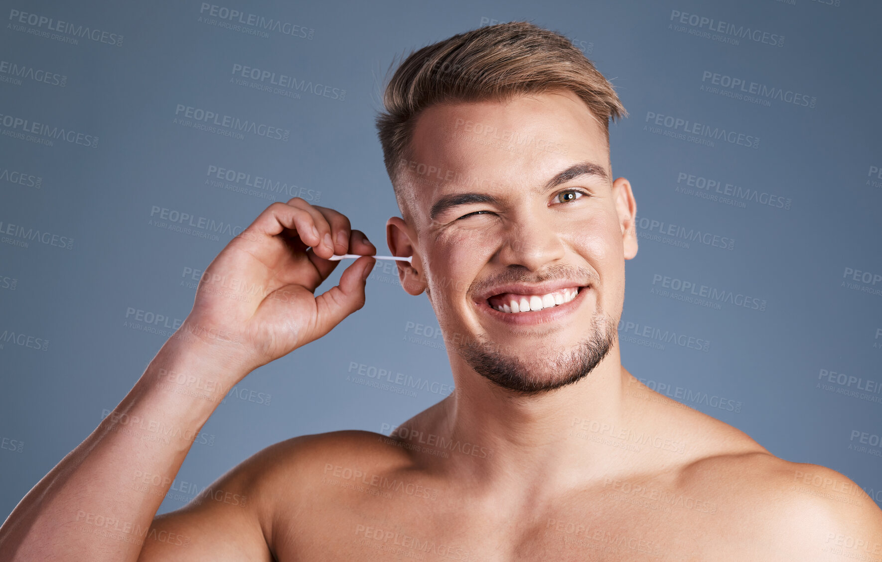 Buy stock photo Shot of a man using a earbud while standing against a grey background