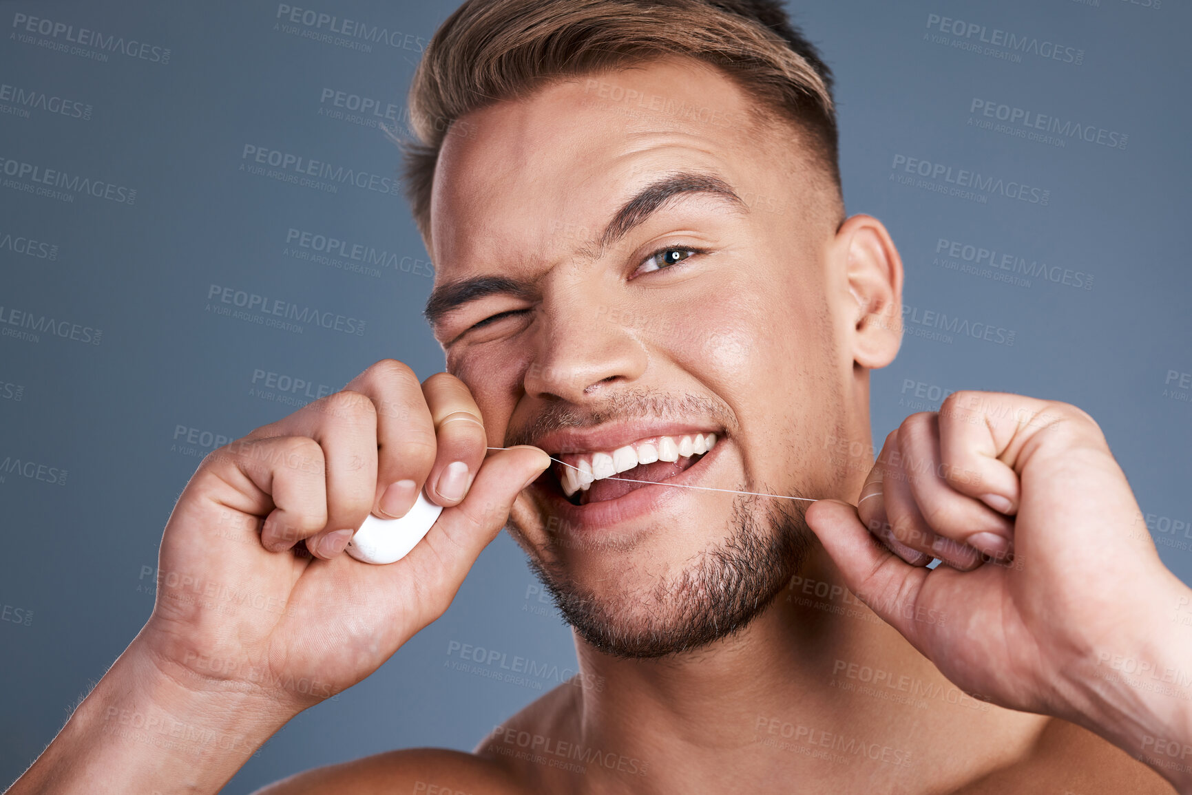 Buy stock photo Studio shot of a handsome young man flossing his teeth against a grey background