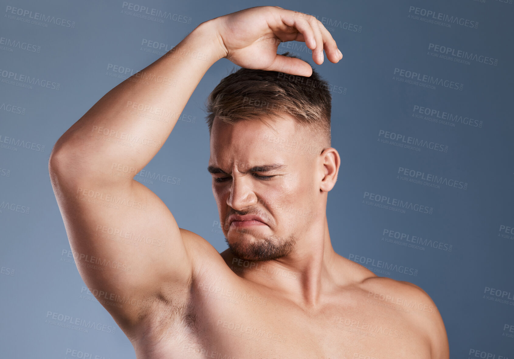 Buy stock photo Studio shot of a young man smelling his armpit against a grey background