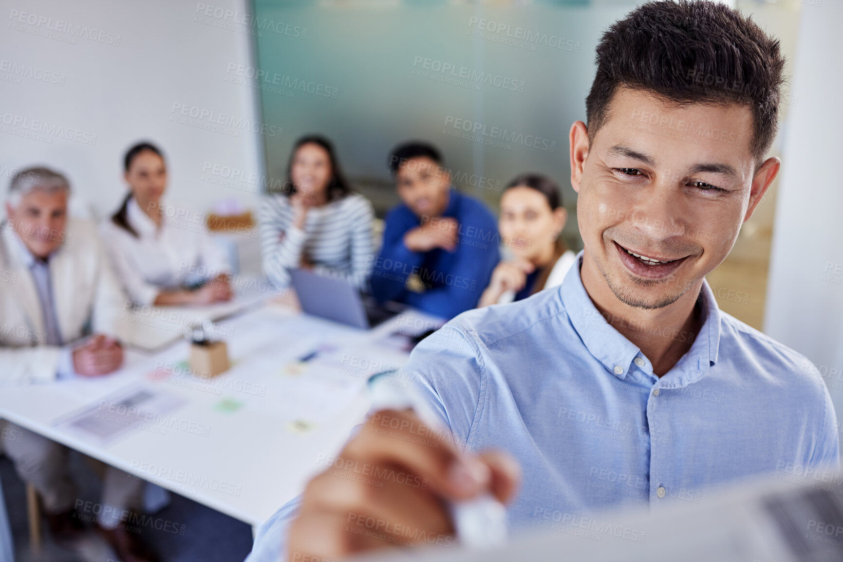 Buy stock photo Shot of a young businessman writing on a board during a meeting at work