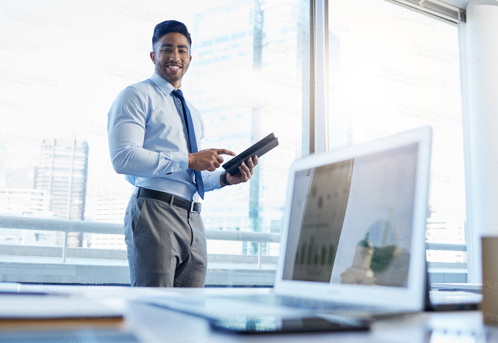 Buy stock photo Shot of a businessman using a digital tablet while standing in his office