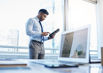 Buy stock photo Shot of a businessman using a digital tablet while standing in his office