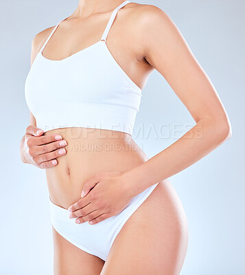 Buy stock photo Shot of an unrecognizable woman posing with her hands around her belly against a grey background