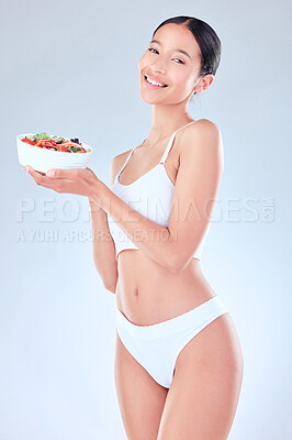 Buy stock photo Studio portrait of a young woman holding a breakfast bowl of fruit  against a grey background