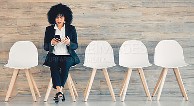 Buy stock photo Shot of a young businesswoman using a phone while waiting in line at an office