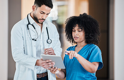 Buy stock photo Shot of two young doctors using a tablet and having a discussion in a modern office