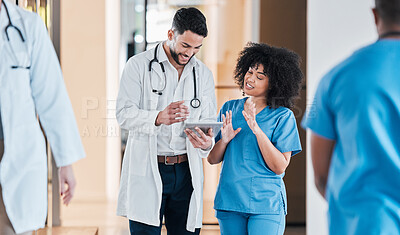 Buy stock photo Shot of two young doctors using a tablet and having a discussion in a modern office