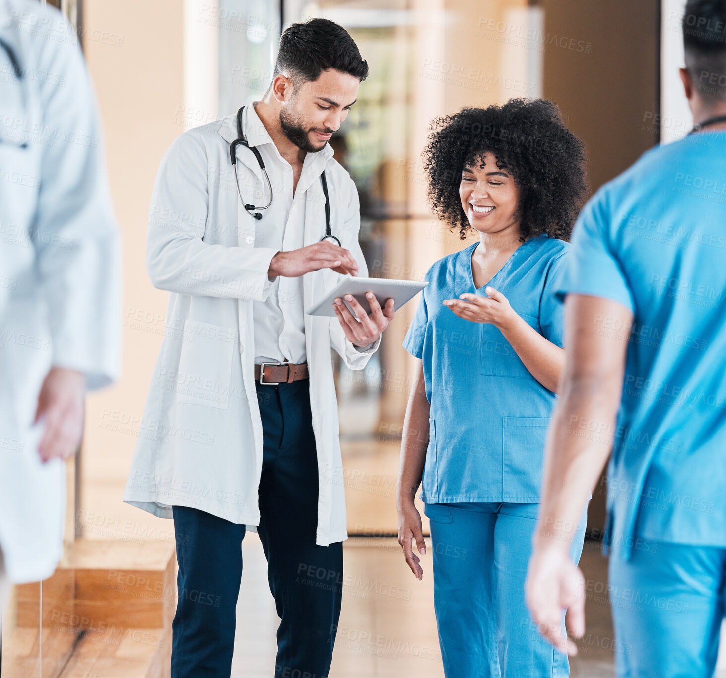 Buy stock photo Shot of two young doctors using a tablet and having a discussion in a modern office