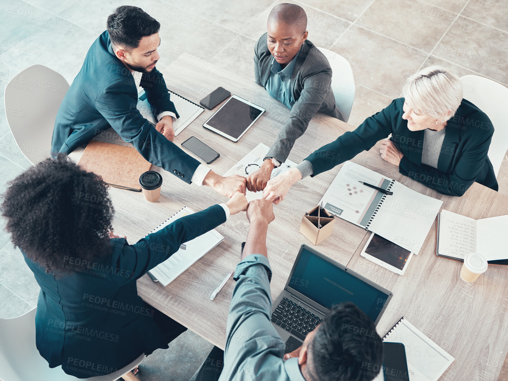 Buy stock photo High angle shot of a diverse group of businesspeople sitting in the office and forming a circle with their fists