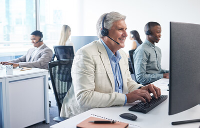 Buy stock photo Shot of a mature businessman using a headset and computer in a modern office