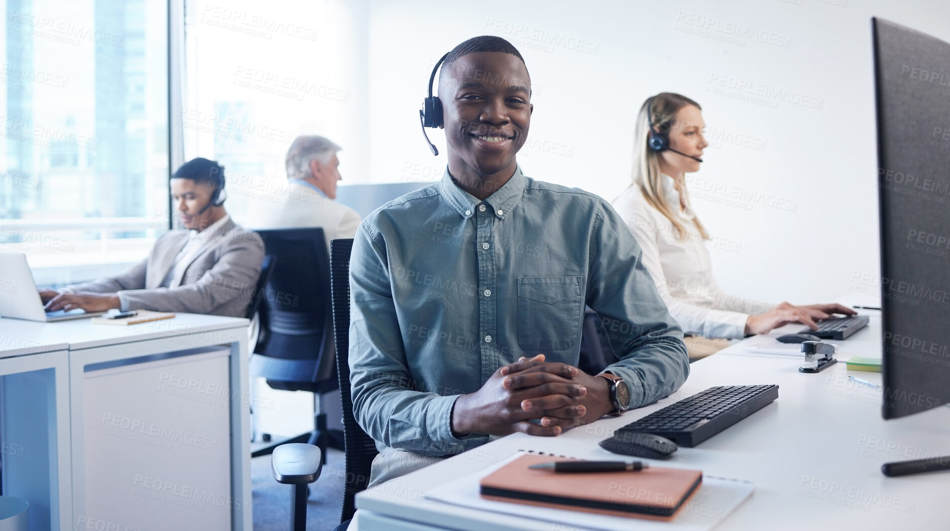 Buy stock photo Portrait of a young businessman using a headset and computer in a modern office
