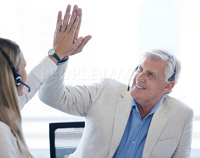 Buy stock photo Shot of a businessman and businesswoman using a headset and giving each other a high five while working in a modern office