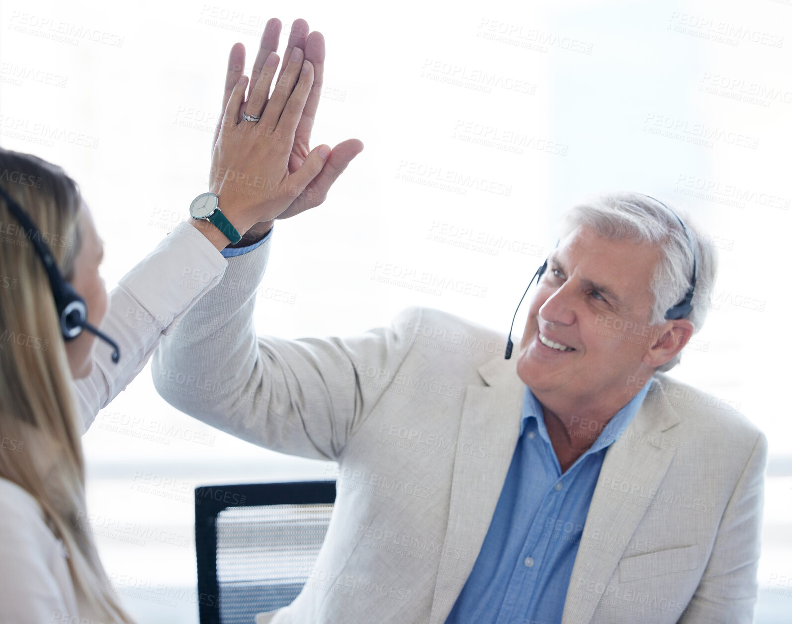 Buy stock photo Shot of a businessman and businesswoman using a headset and giving each other a high five while working in a modern office