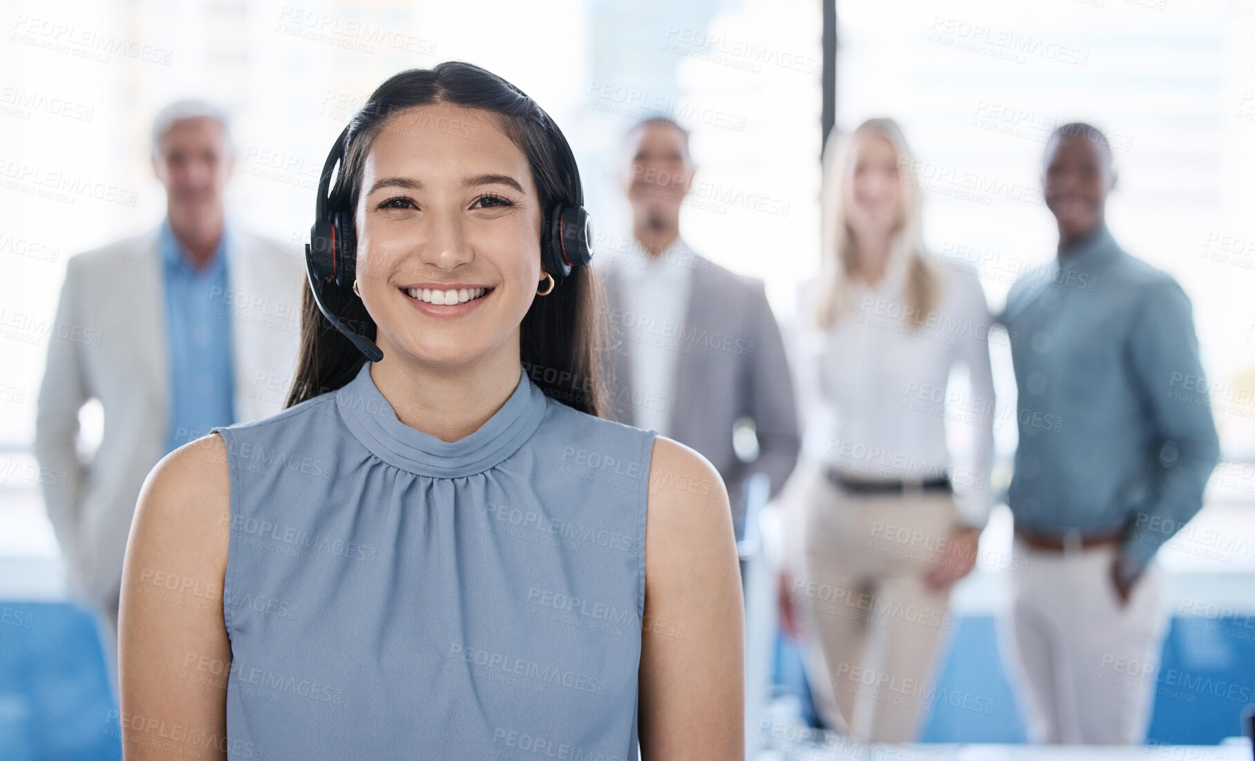 Buy stock photo Portrait of a young businesswoman using a headset in a modern office with her team in the background