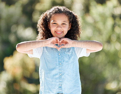 Buy stock photo Shot of a little girl forming a heart shape with her hands while standing outside