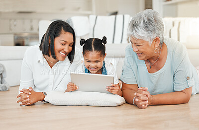 Buy stock photo Shot of a young family happily bonding while using a digital tablet at home