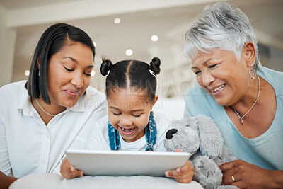 Buy stock photo Shot of a young family happily bonding while using a digital tablet at home