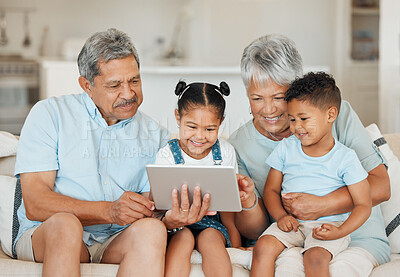 Buy stock photo Shot of grandparents bonding with their grandchildren and using a digital tablet on a sofa at home