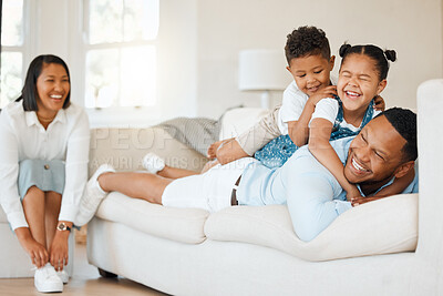 Buy stock photo Shot of a young couple sitting on their sofa at home with their children
