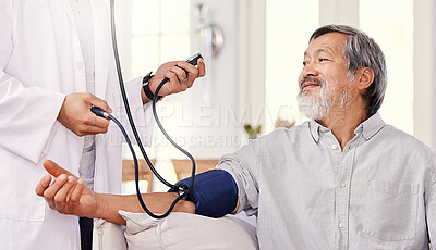 Buy stock photo Shot of a male doctor examining a senior patient with a blood pressure gauge