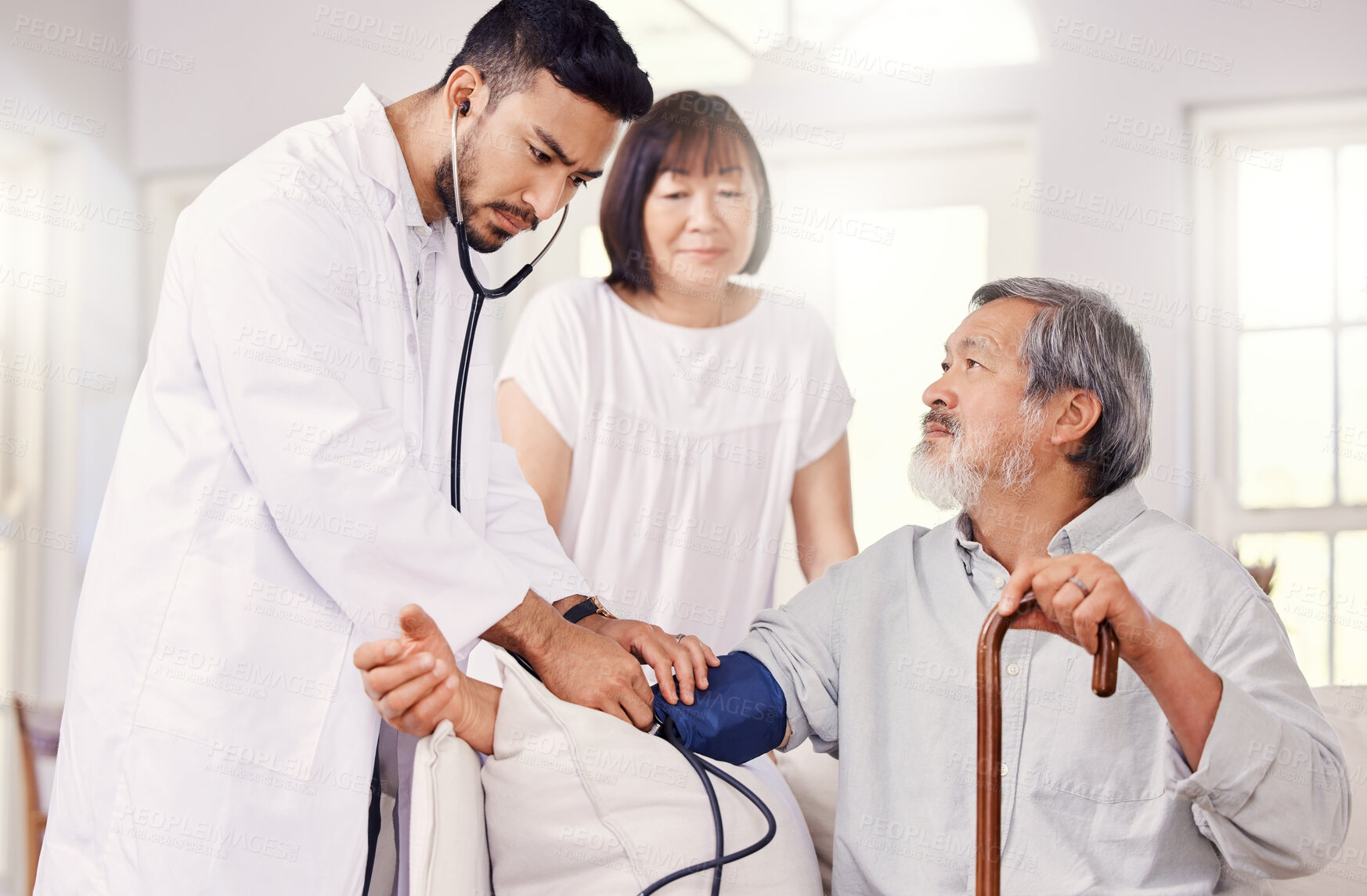 Buy stock photo Shot of a male doctor examining a senior patient with a blood pressure gauge