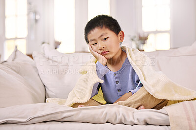 Buy stock photo Shot of an adorable little boy looking displeased while sitting at home