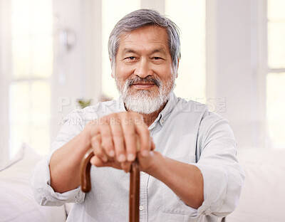 Buy stock photo Shot of a senior man sitting at home with a wooden walking stick