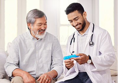 Buy stock photo Shot of a doctor holding a pill box while talking to a senior patient