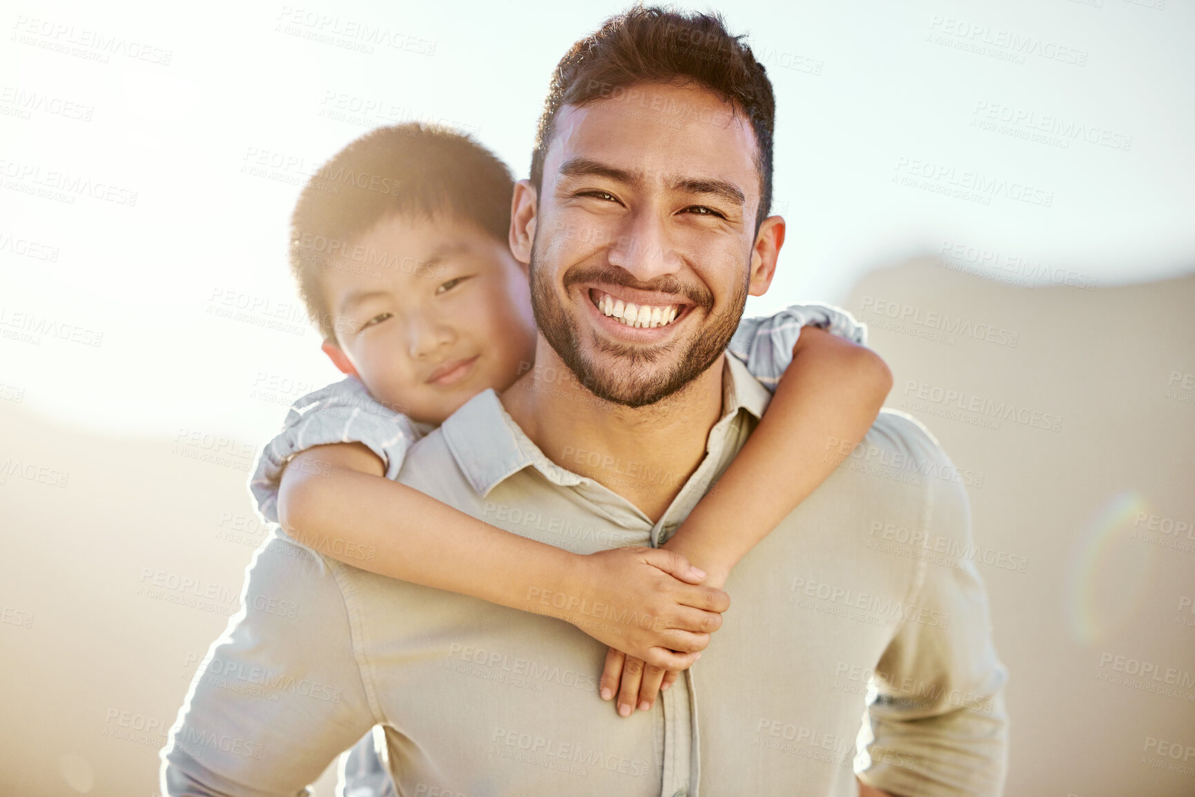 Buy stock photo Cropped portrait of a handsome young man piggybacking his son on the beach