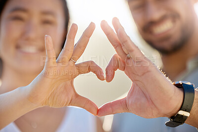 Buy stock photo Cropped shot of an affectionate young couple making a heart shape with their hands on the beach