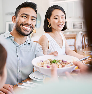 Buy stock photo Shot of a young couple have some lunch with the family at home