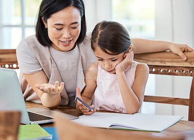 Buy stock photo Shot of a young mother helping her daughter with her homework at home