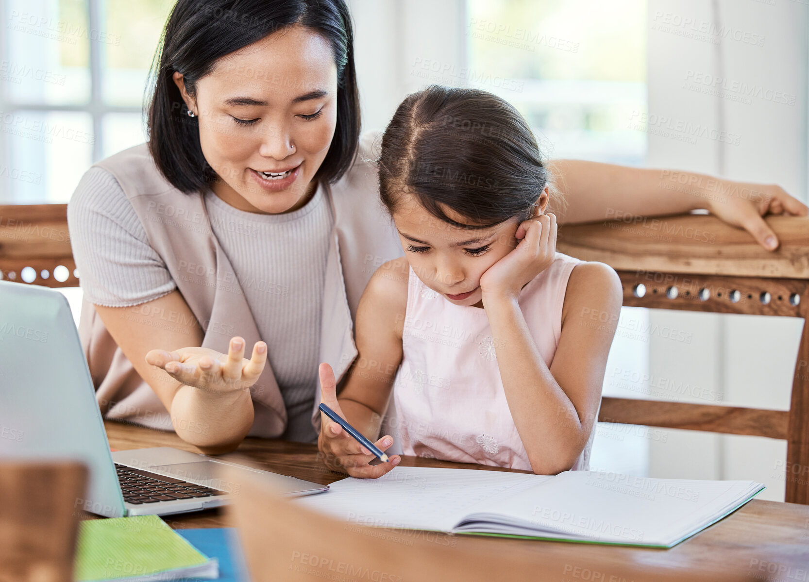 Buy stock photo Shot of a young mother helping her daughter with her homework at home