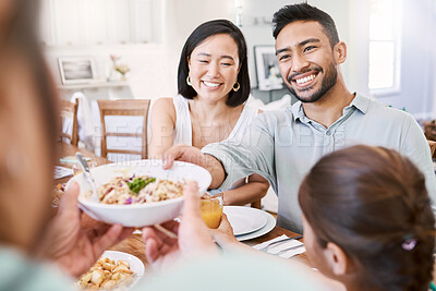 Buy stock photo Shot of a young couple have some lunch with the family at home