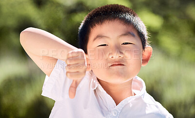 Buy stock photo Shot of a little boy showing thumbs down in a garden