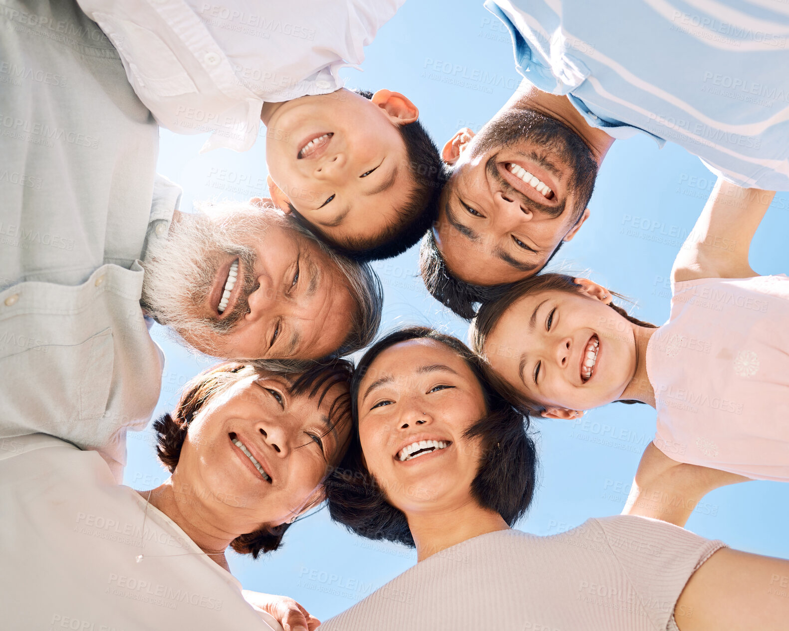 Buy stock photo Low angle shot of a happy family huddled together outdoors