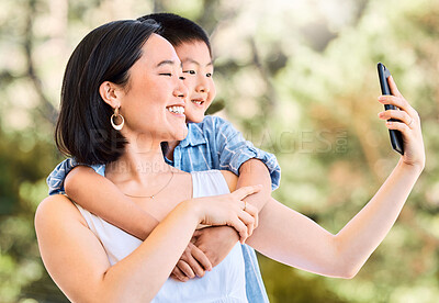Buy stock photo Shot of a happy young mother and her adorable little boy taking selfies in a garden