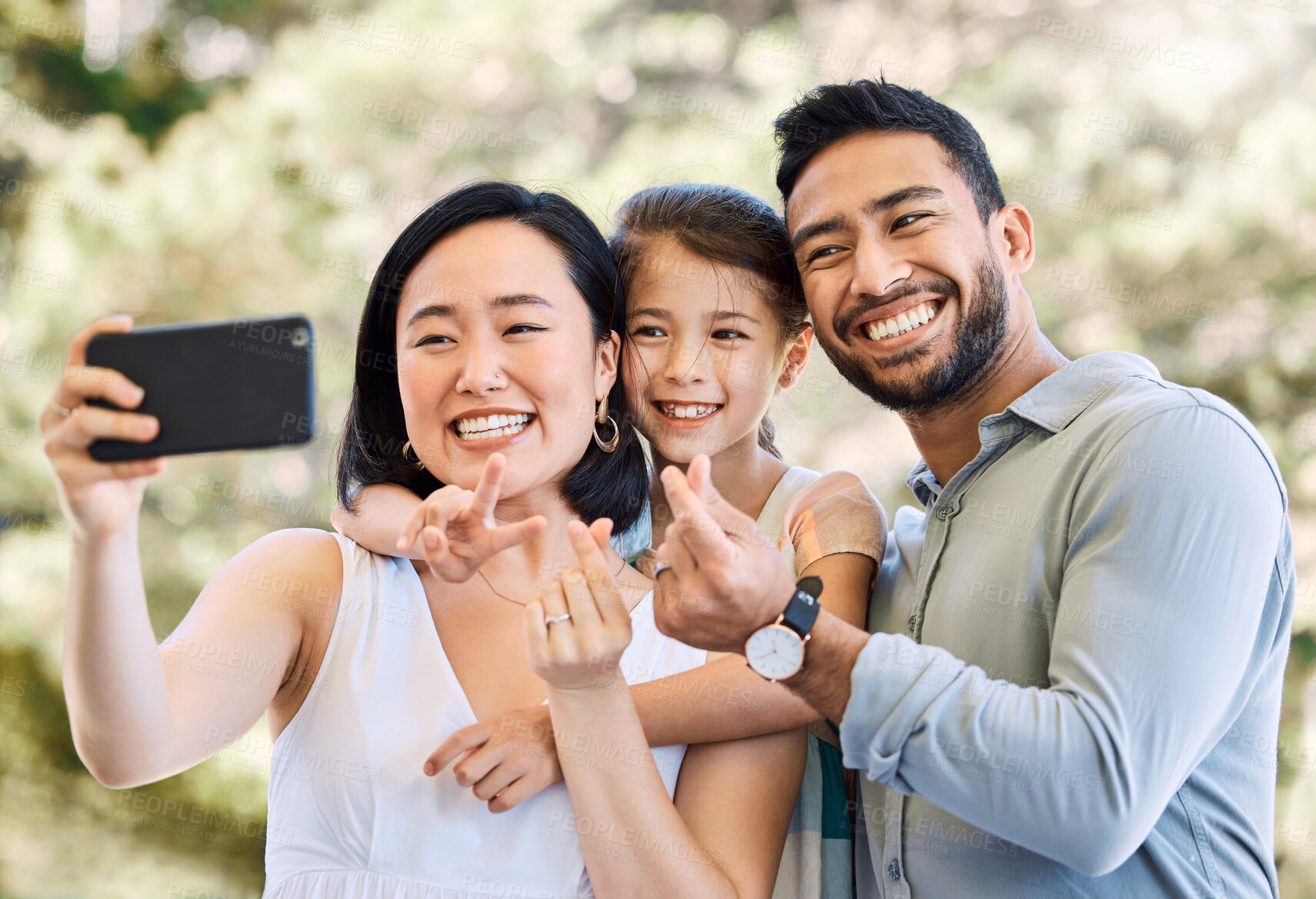 Buy stock photo Shot of a happy young family taking selfies in a garden