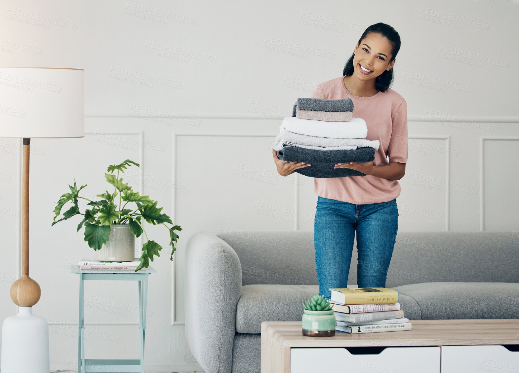 Buy stock photo Woman, home and happy portrait with laundry, living room and towels for housekeeping or cleaning service. Hospitality, helping for apartment maintenance, washing or clean clothes for chores or job