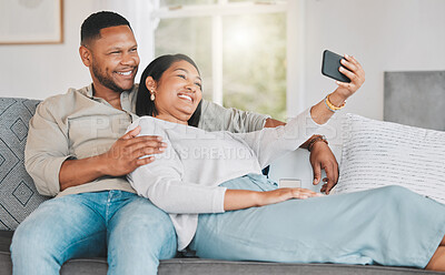 Buy stock photo Shot of a young couple taking selfies while relaxing together at home