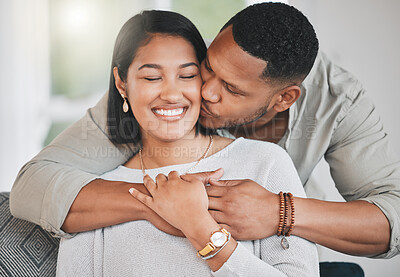Buy stock photo Shot of a young man giving his wife a kiss on the cheek at home