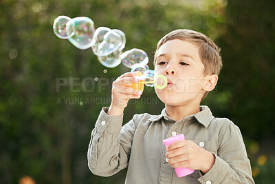 Buy stock photo Shot of an adorable little boy blowing bubbles outside