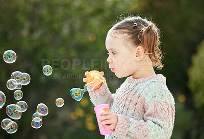 Buy stock photo Shot of an adorable little girl blowing bubbles outside