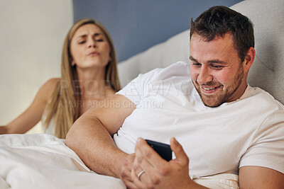 Buy stock photo Phone, bed and man with angry wife for cheating, infidelity or affair communication online at home. Marriage conflict, argument and happy male person network on cellphone with upset woman in bedroom.