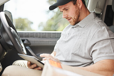 Buy stock photo Cropped shot of a handsome young delivery man using a tablet while sitting in his van